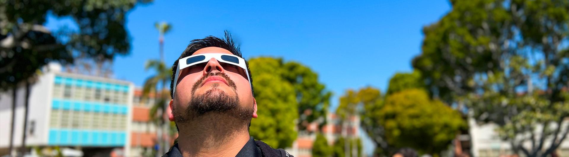 ɫ staffer looks through eclipse glasses